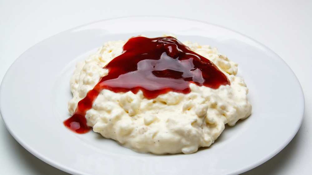 Creamy rice pudding on a white plate topped with a red fruit coulis