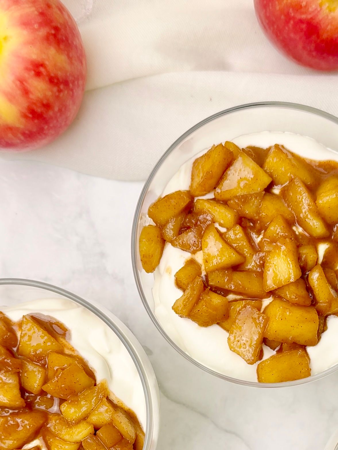 Clear verrines layered with caramelized apples and airy mascarpone cream, topped with a mint sprig.
