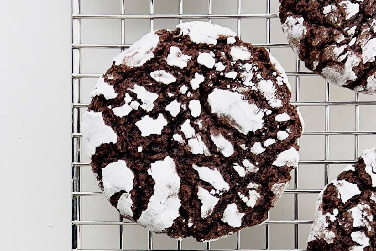 Close-up of chocolate-covered dates, one cut in half revealing the inside, on parchment paper with cocoa powder dusting.
