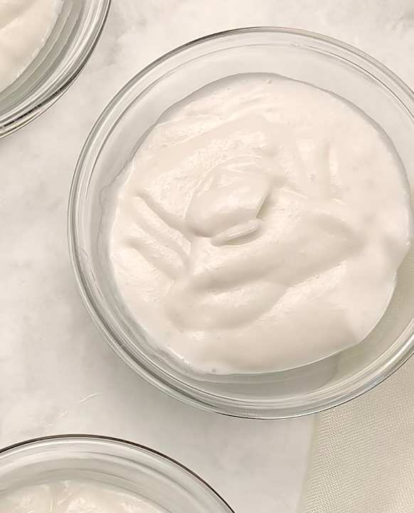 Vue de dessus de deux bols en verre remplis d'un dessert blanc et crémeux. Celui du haut est net, l'autre, en bas à gauche, est partiellement visible.