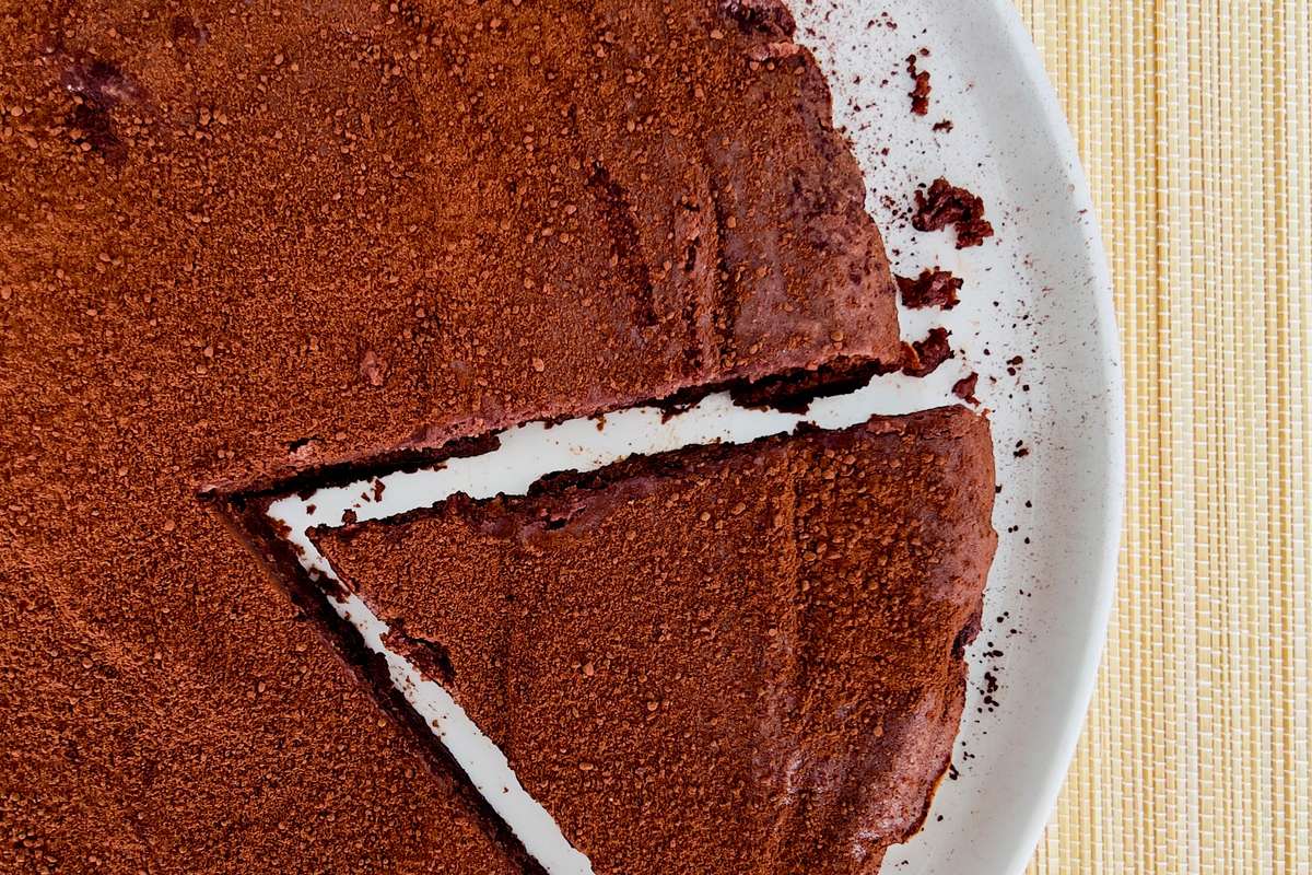 Une tranche de riche gâteau au chocolat et à la ricotta, montrant sa texture moelleuse et sa couleur sombre.