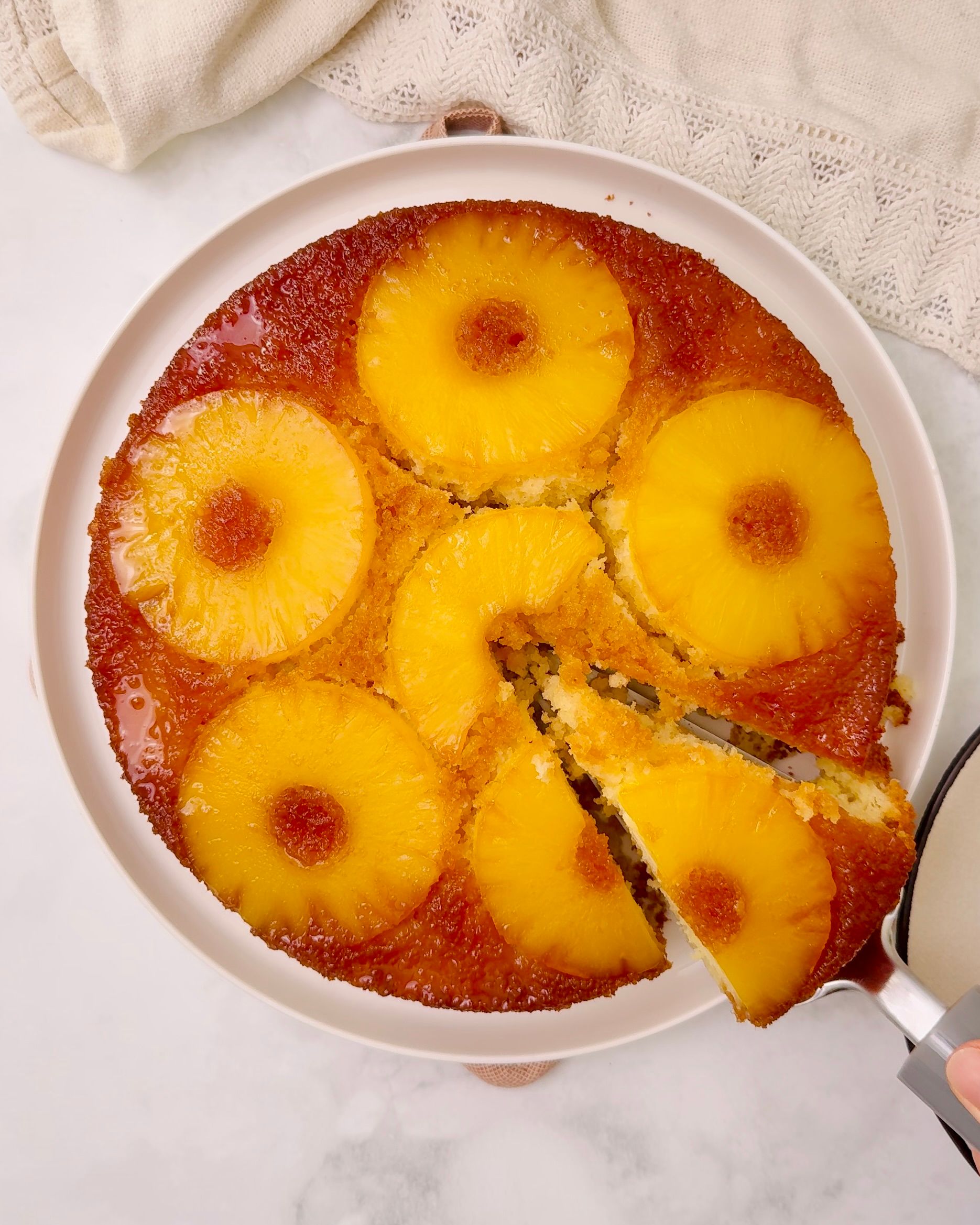 Two sliced pieces of an apple dessert on a brown plate with a gold spoon, and whole apples in the top right corner.