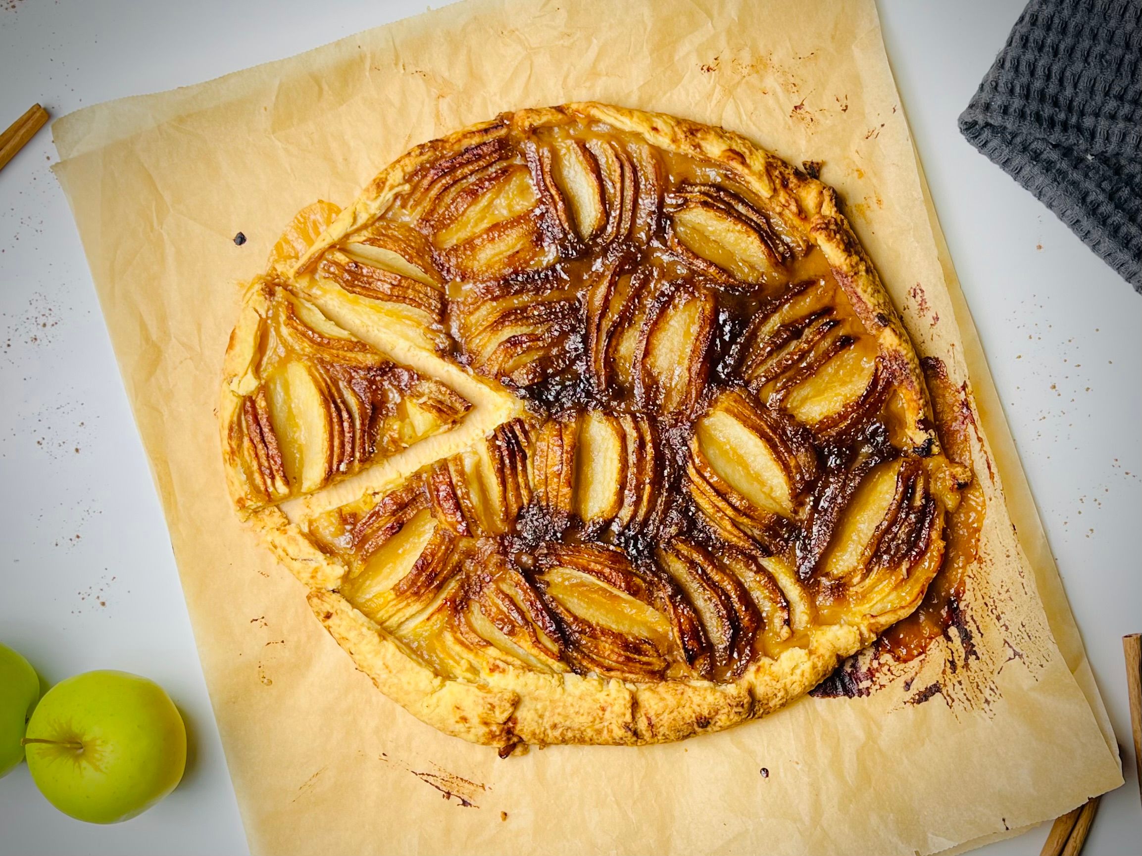 A rustic apple tart with thinly sliced apples arranged in a spiral pattern on a golden crust.