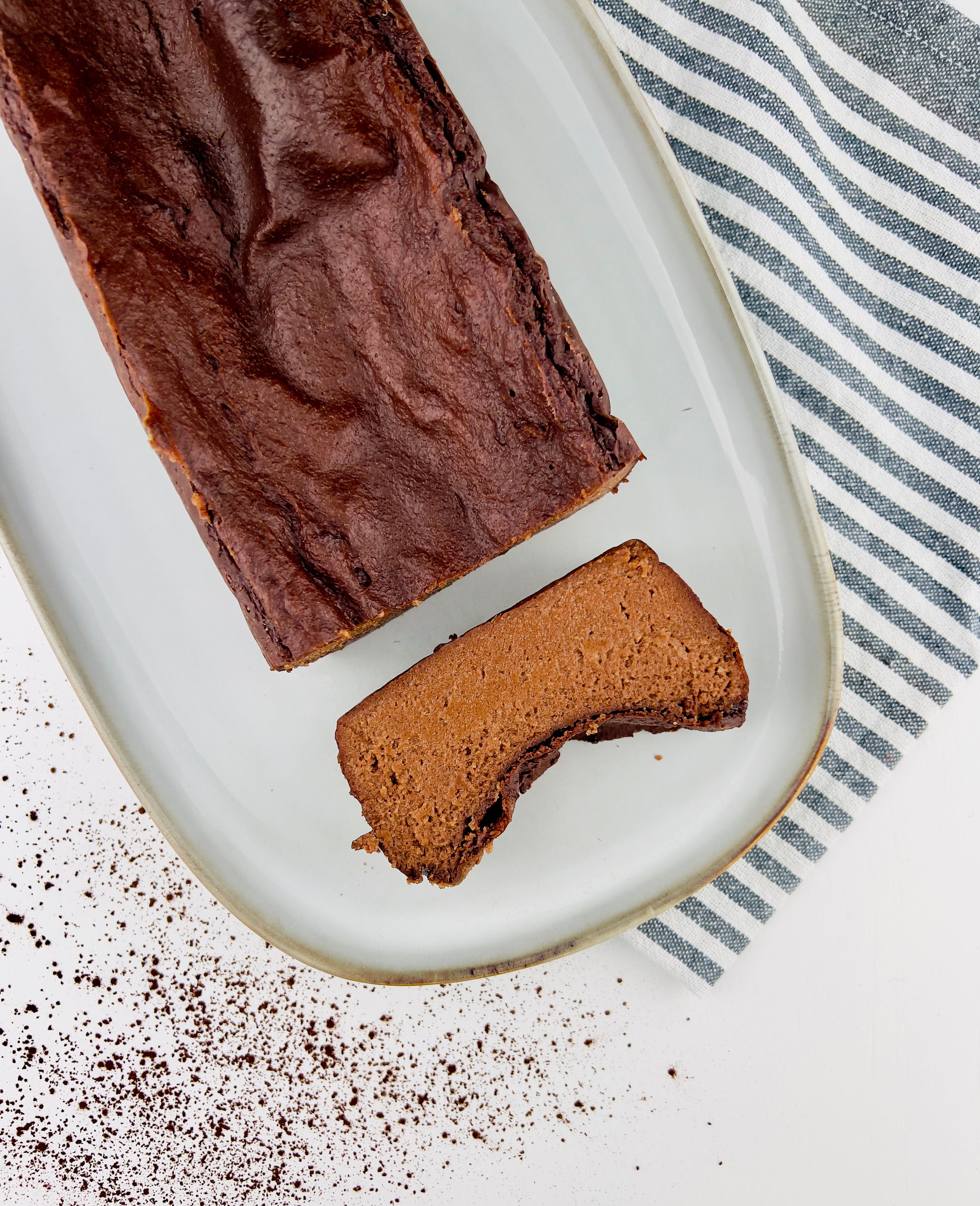 Close-up of a fig upside-down cake topped with glistening caramelized fig slices, on a white plate, partially sliced.