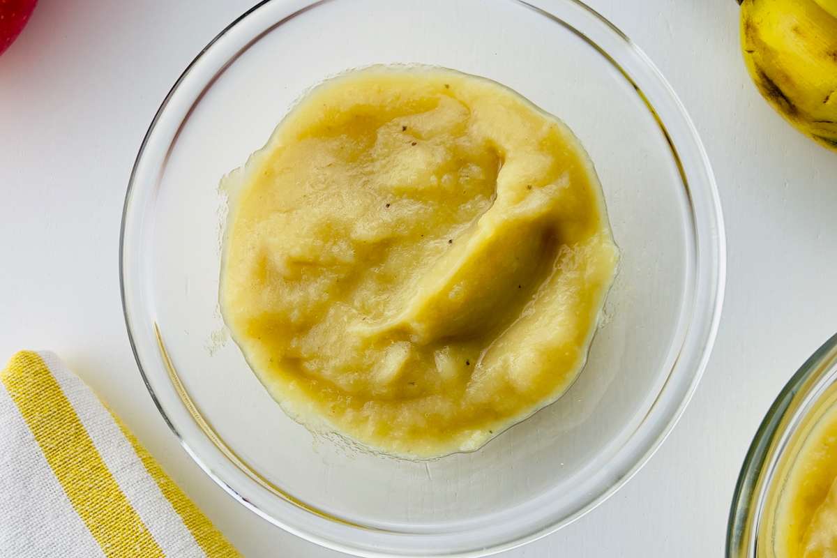 Delicious apple crumble with golden topping served in a white dish, with a scoop revealing warm apple filling.